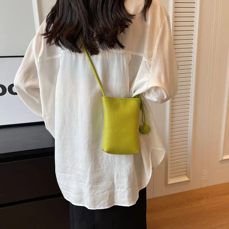 Camisa blanca oversize con bolso de cuero verde lima colgando del escote.
