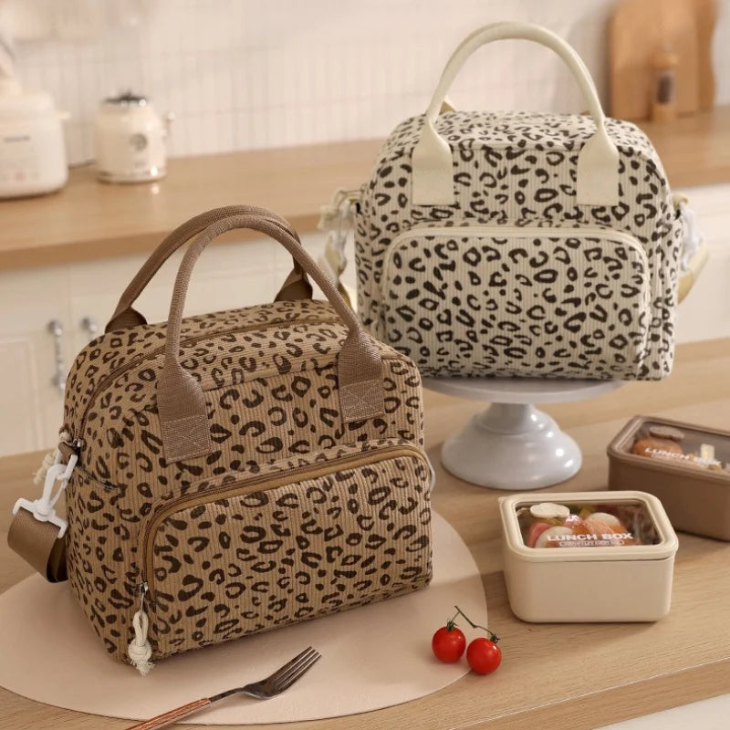 A brown floral corduroy insulated lunch bag with a leopard print pattern sits on a wooden table.