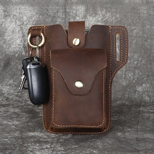Bolso de cuero marrón genuino para hombre con solapa y asa para llaves, sobre fondo gris.