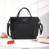 Black insulated lunch bag with a woven pattern and gold accents resting on a white table.