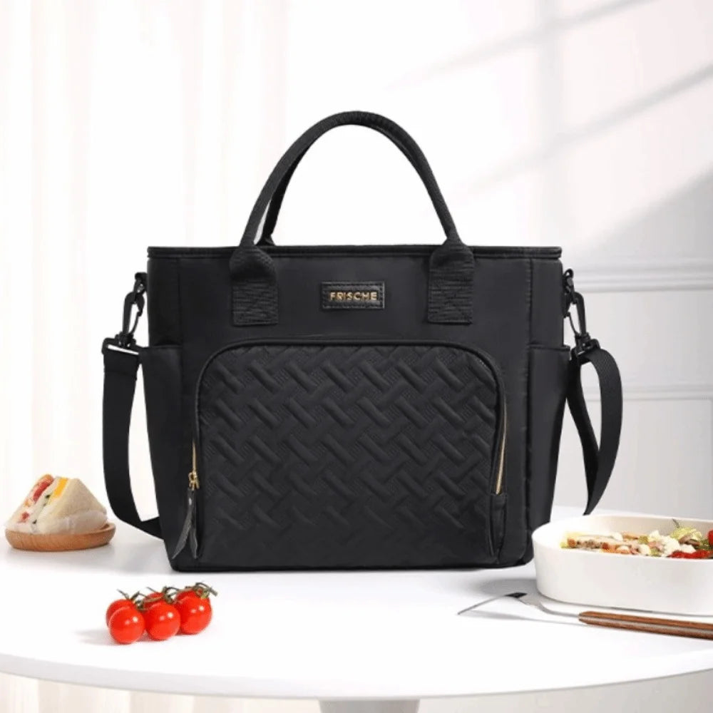 Black insulated lunch bag with a woven pattern and gold accents resting on a white table.