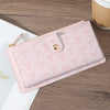 A pink elegant folding multi-card wallet with a zipper and decorative bows resting on a wooden surface.