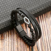 A black leather bracelet featuring a braided design and tiger eye beads resting on a wooden surface.