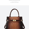 A brown crocodile embossed leather shoulder handbag with a gold buckle and matching strap.