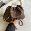 A brown PU leather chain shoulder bag with a gold-toned chain strap is held by a hand on a white surface.