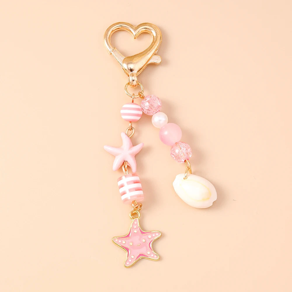 Gold heart-shaped keychain featuring a starfish and various pink and white pearl accents