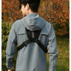 A person wearing a light blue tactical chest rig vest bag for outdoor gear in an outdoor setting.