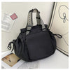 A black nylon shoulder bag with patterned straps is shown next to some papers and a notebook.