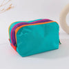 A teal lightweight travel makeup bag with purple and orange accents is shown on a white surface.