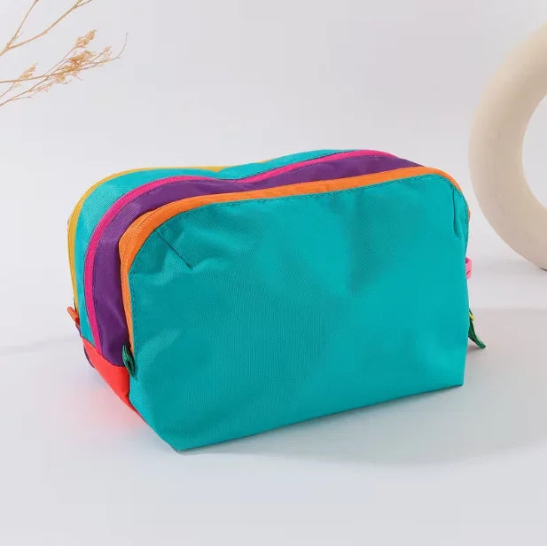A teal lightweight travel makeup bag with purple and orange accents is shown on a white surface.