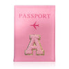 A pink leather passport holder with a gold initial A embossed on the cover.