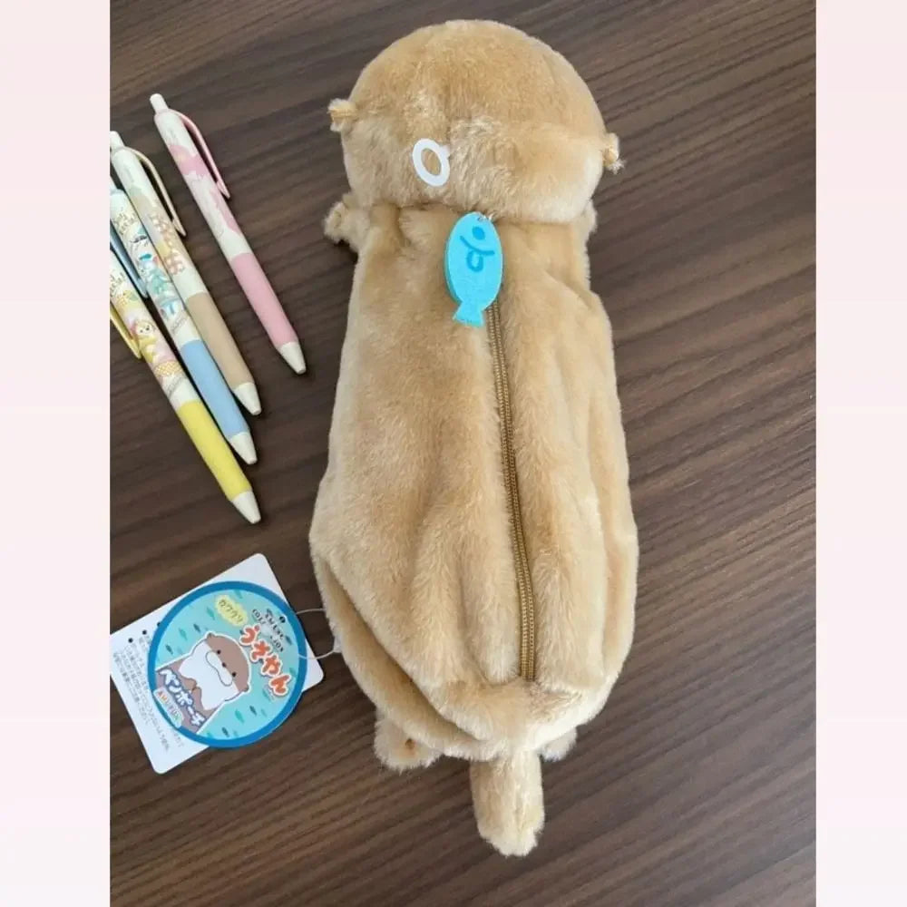 A fluffy brown otter plush pencil case with a zipper and a light blue tag is shown on a wooden surface.