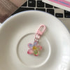 A pink resin flower keychain rests on a white ceramic plate.