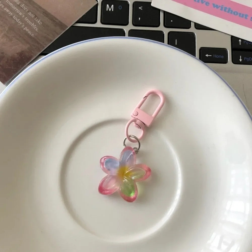 A pink resin flower keychain rests on a white ceramic plate.