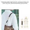 A brown leather crossbody bag with a gold chain and charm decoration is shown against a white shirt.