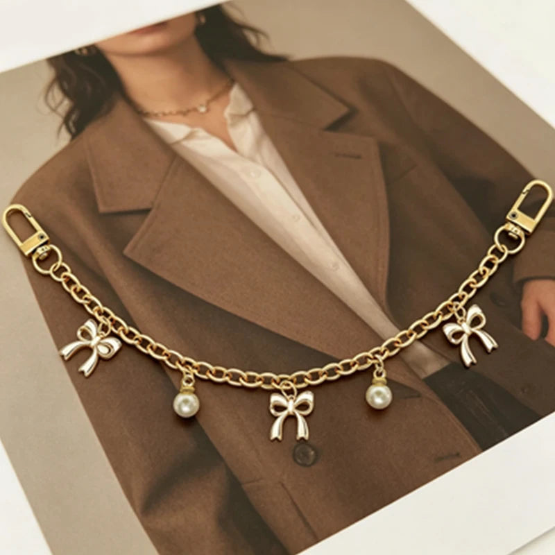 Gold chunky chain necklace with pearl charms displayed against a brown blazer.