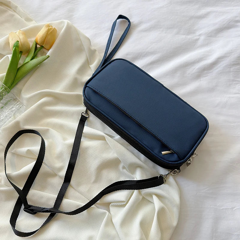 A navy blue multi-pocket waterproof travel document organizer with a black strap is displayed on a white fabric background.