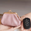 A pink leather coin purse with a gold-tone clasp and chain attached to a black keychain is held in a hand.