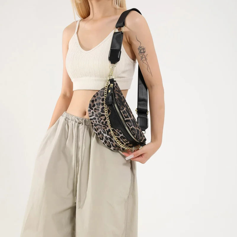 Eine Frau trägt ein cremefarbenes Crop-Top und beige Hosen und hält eine leopardprintierte Umhängetasche.