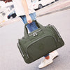A woman is carrying a olive green durable nylon travel duffle bag on her shoulder while walking outdoors.