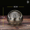 Vintage metal ashtray with a rose embossing design shown on a wooden surface.
