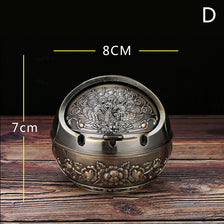 Vintage metal ashtray with a rose embossing design shown on a wooden surface.