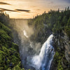 Dramatische Landschaft mit Wasserfall, der über eine Klippe stürzt, inmitten von dichtem Wald und atmosphärischem Nebel unter