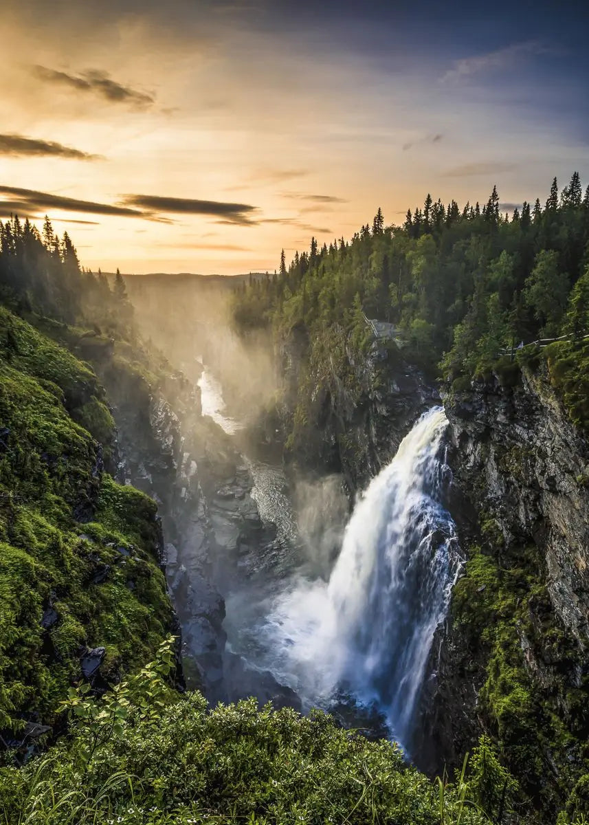 Dramatische Landschaft mit Wasserfall, der über eine Klippe stürzt, inmitten von dichtem Wald und atmosphärischem Nebel unter