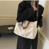 A woman holds a cream-colored lightweight nylon tote bag with brown leather straps and multiple pockets.