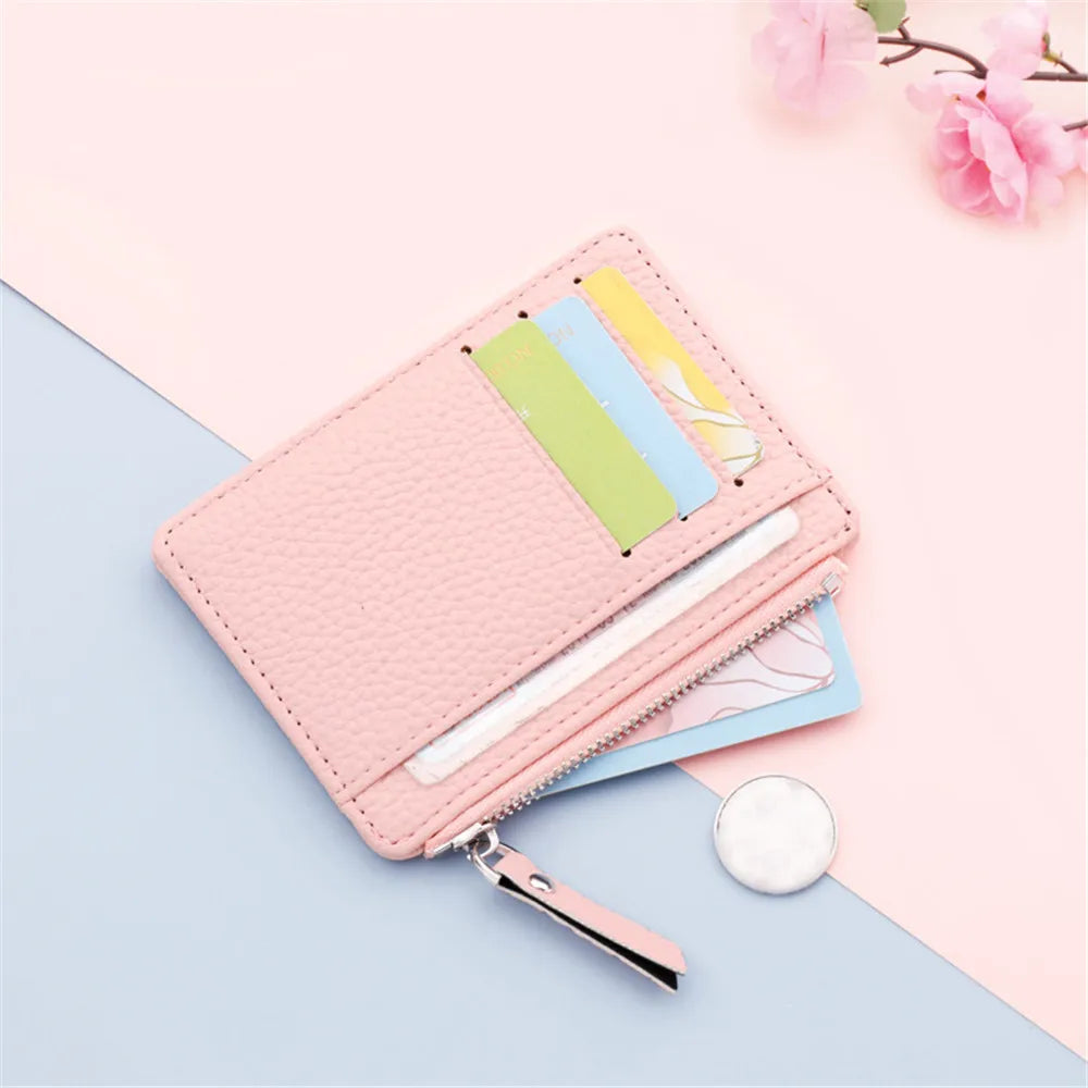 A pink PU leather card holder wallet with a zipper and keychain is shown against a light blue background.