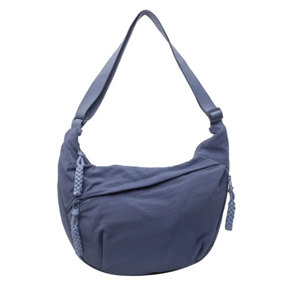 A slate blue canvas crossbody bag with a long strap shown against a white background.