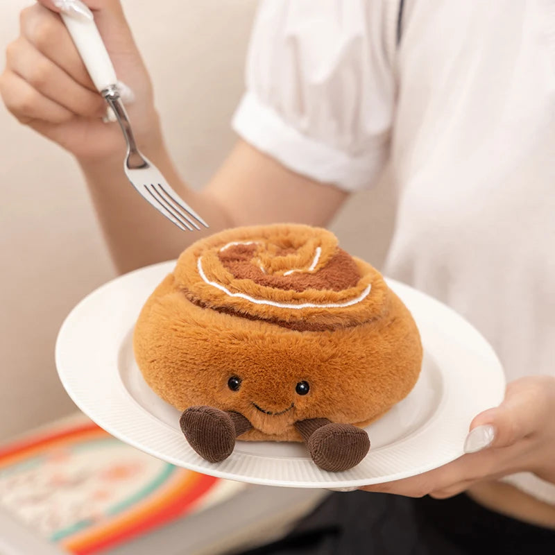 A hand holds a round, brown cartoon character plush toy on a white plate.