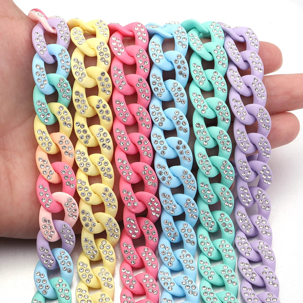 A hand holds a colorful acrylic link chain featuring various pastel colors like pink, yellow, blue, and purple.