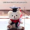 A white plush bear dressed in a graduation cap and gown, holding a camera and glasses.