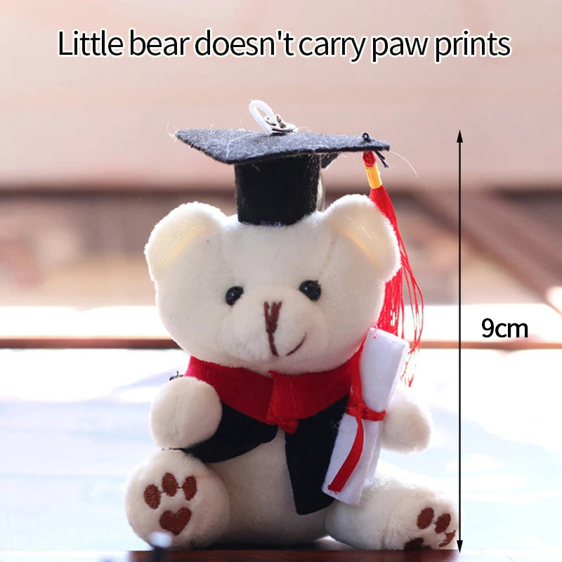 A white plush bear dressed in a graduation cap and gown, holding a camera and glasses.