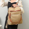 A woman models a beige vintage tassel backpack with brown leather accents against a light gray background.