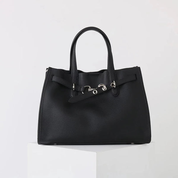 A black genuine leather women's shoulder tote bag with a top handle displayed on a white pedestal.