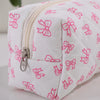 Bolsa de maquillaje blanca con estampado de lazo rosa y textura acolchada.