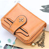 A tan PU leather compact wallet with a zipper and chain is shown next to a white box and a pair of black shoes.