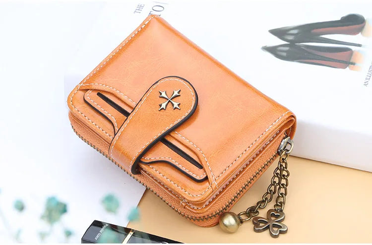 A tan PU leather compact wallet with a zipper and chain is shown next to a white box and a pair of black shoes.
