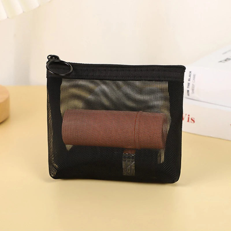 A black toiletry bag with a clear mesh window and a rolled brown item inside.