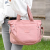 A person holds a pink durable nylon tote bag with a secure zipper closure against a blurred outdoor background.