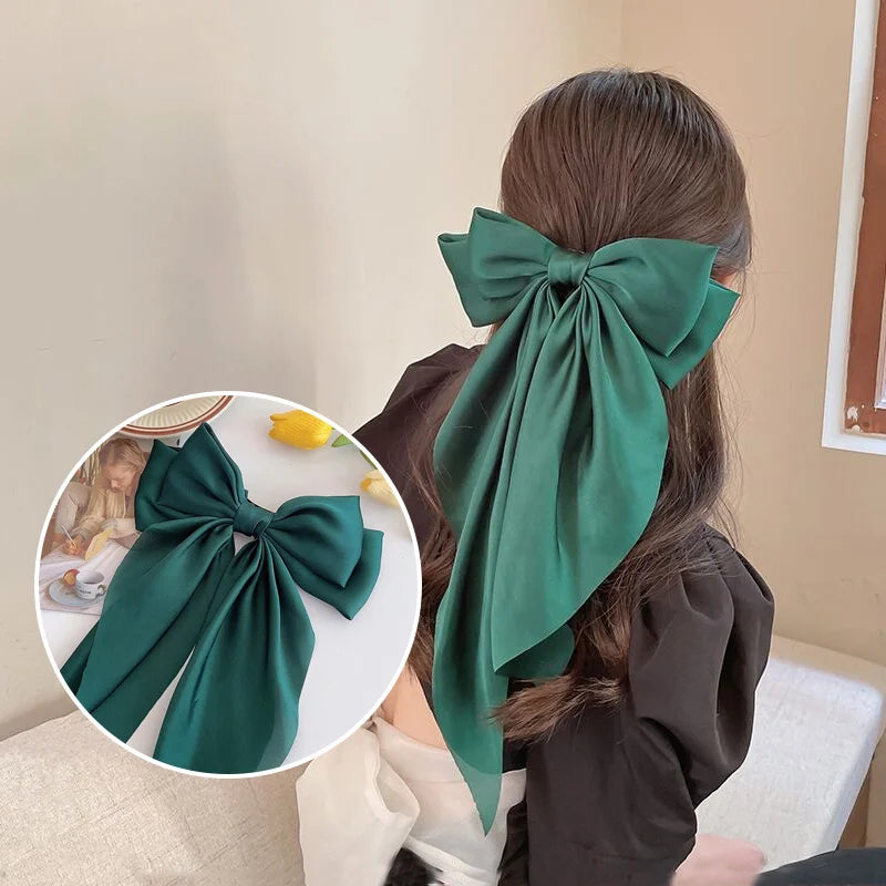 A dark emerald green silk bow hair clip tied in a large bow, shown against a light background.
