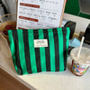 Una bolsa de almacenamiento de lona a rayas negras y verdes se muestra en una encimera junto a una taza.