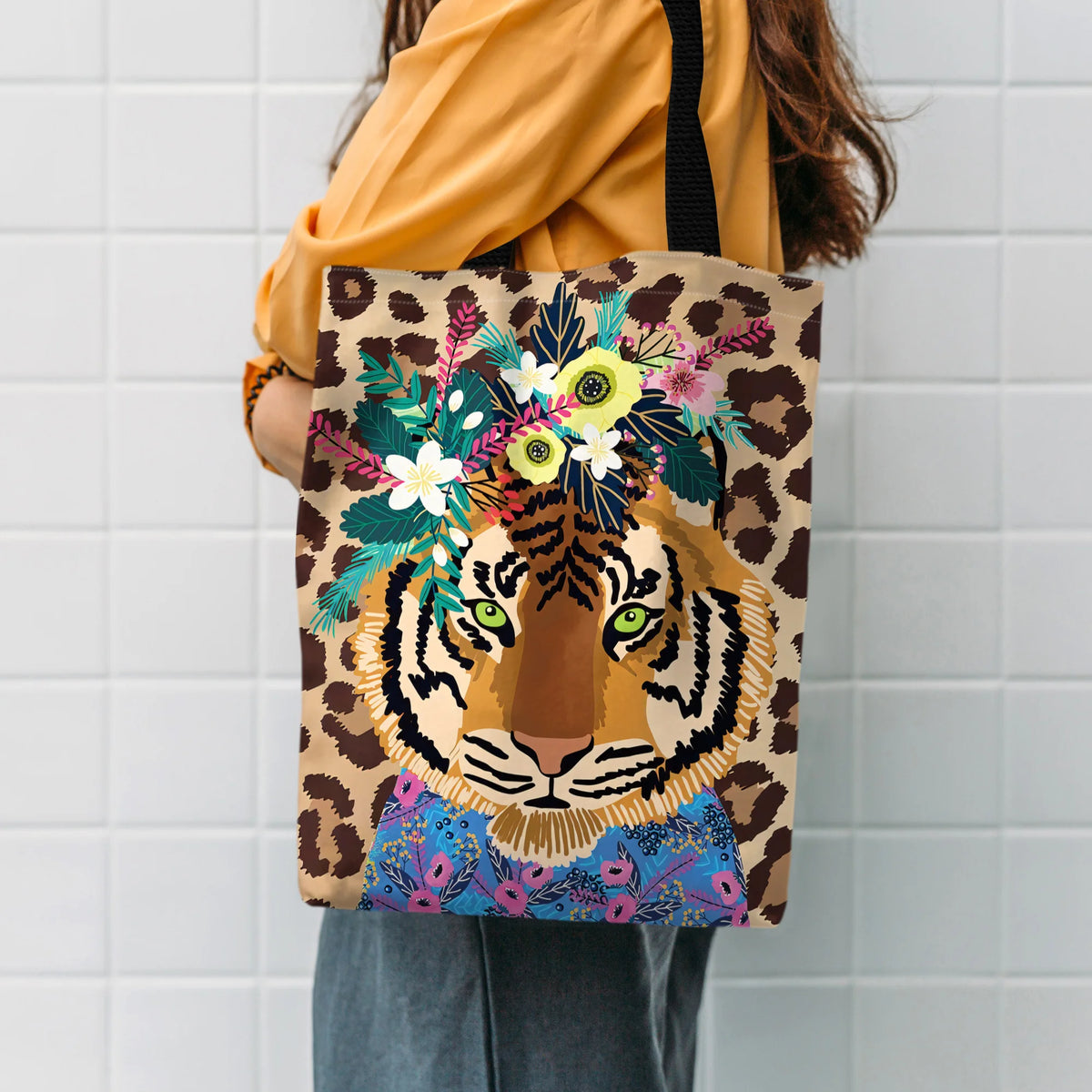 A canvas tote bag featuring a leopard print background with an illustration of a tiger head surrounded by colorful floral wre