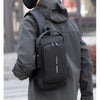 A person wearing a gray jacket is holding a black anti-theft crossbody chest bag.