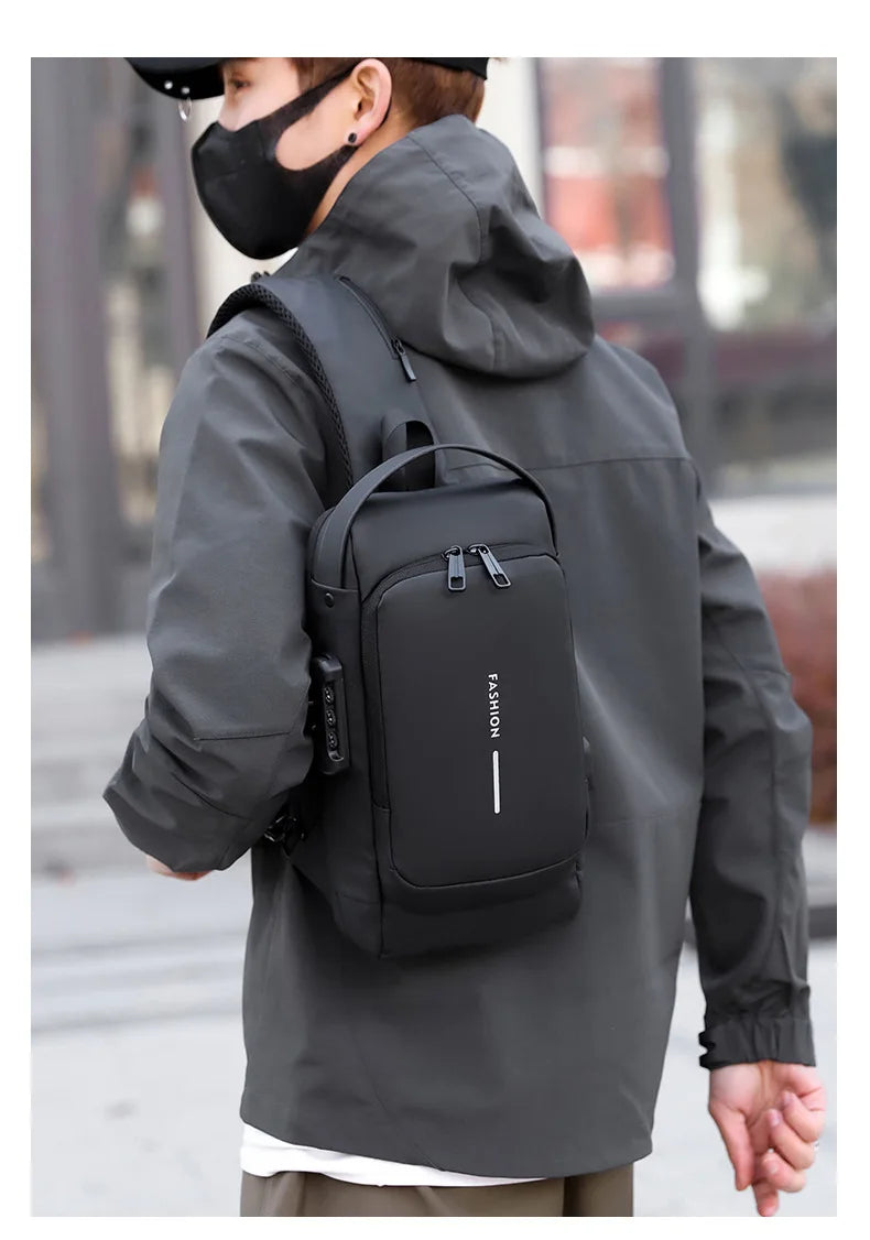 A person wearing a gray jacket is holding a black anti-theft crossbody chest bag.