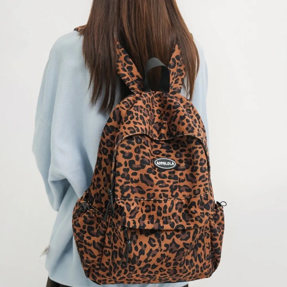 A brown leopard print laptop backpack with black padded straps worn by a person.