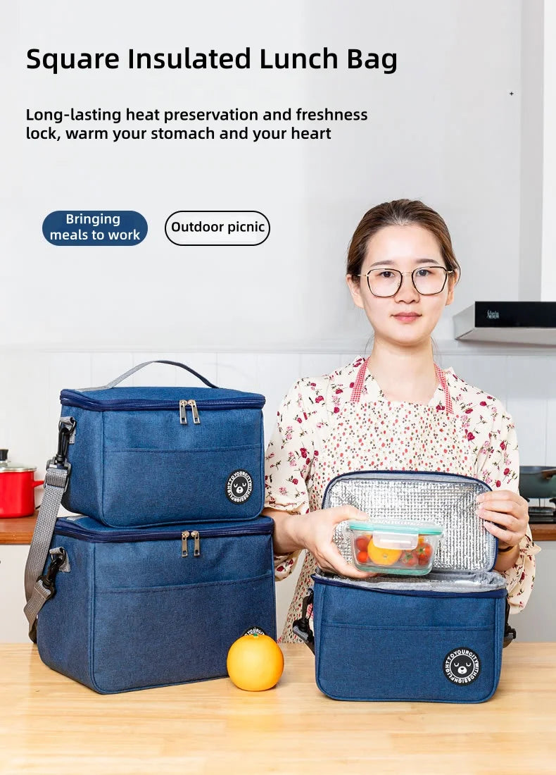 Eine Frau hält eine blaue isolierte Lunchtasche auf einem Holztable mit einer orangen Frucht daneben.