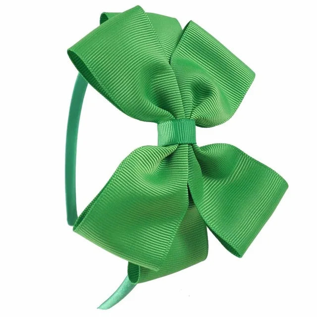 A green satin bow headband is shown against a white background.